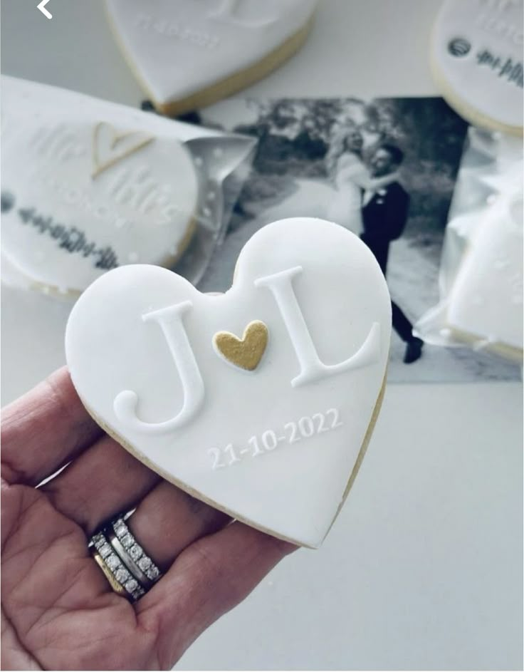 a person holding a heart shaped cookie in their hand with the initials jl on it