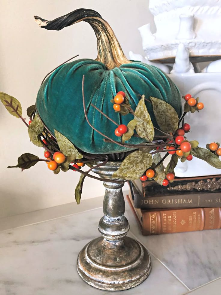 a decorative pumpkin sitting on top of a table next to two books and a vase