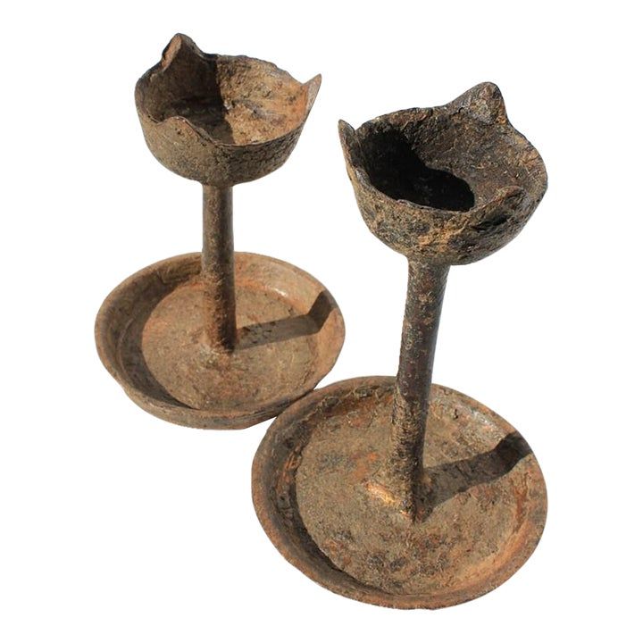 two rusty metal candlesticks sitting on top of each other in front of a white background