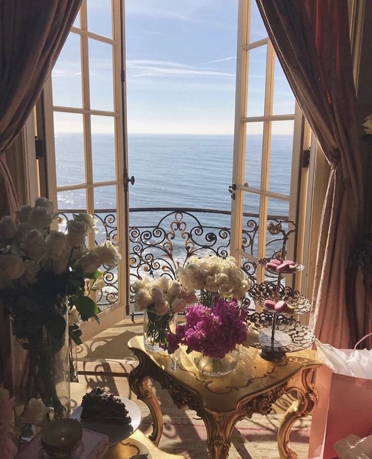 a living room filled with lots of furniture and flowers on top of a window sill