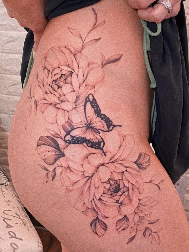 a woman's thigh with flowers and a butterfly on the bottom part of her leg