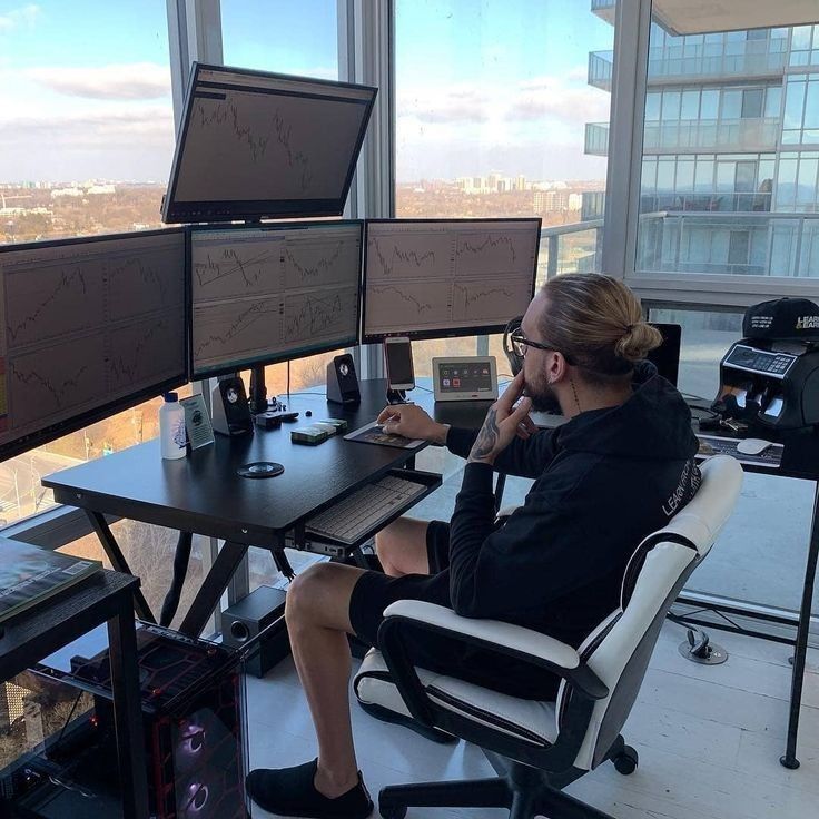 a woman sitting at a desk in front of three computer monitors on top of a table