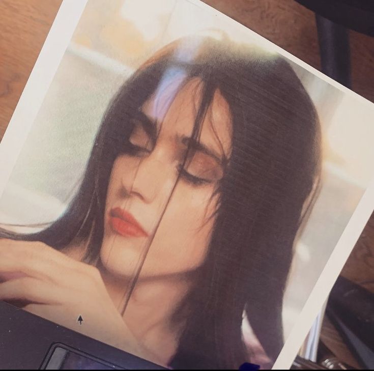 a woman's face is reflected in the image of her laptop computer, which sits on a desk