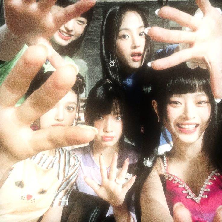 a group of young women standing next to each other with their hands in the air