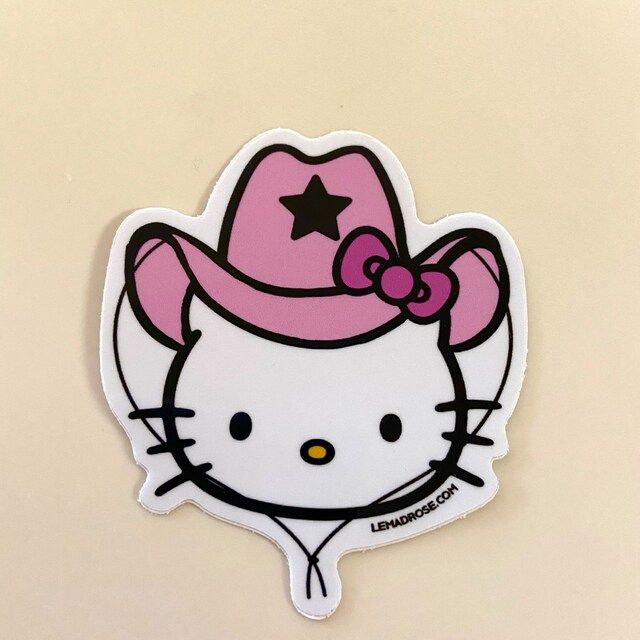 a hello kitty sticker with a pink hat on it's head and stars