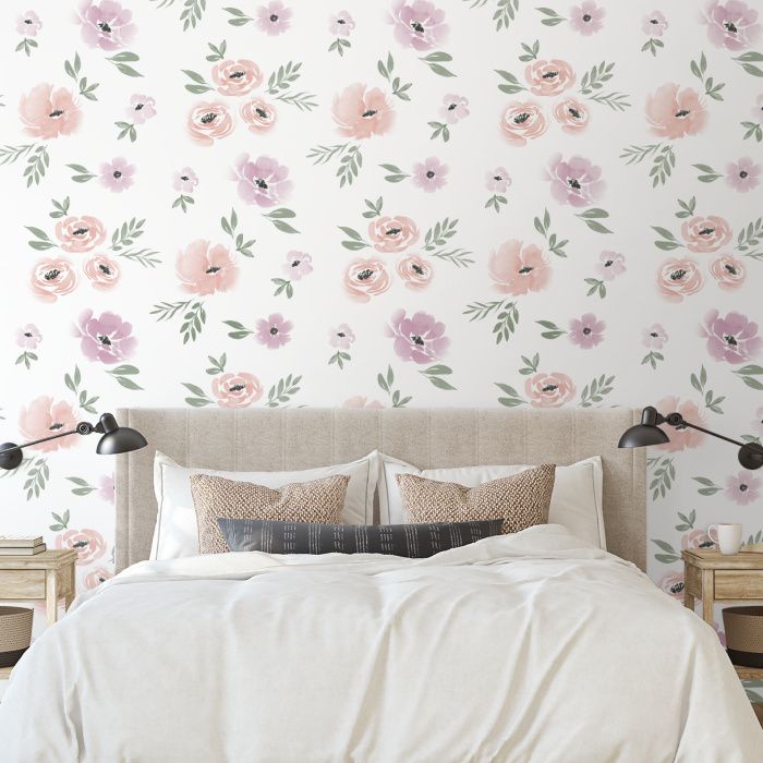 a white bed sitting next to a wall with pink and green flowers painted on it