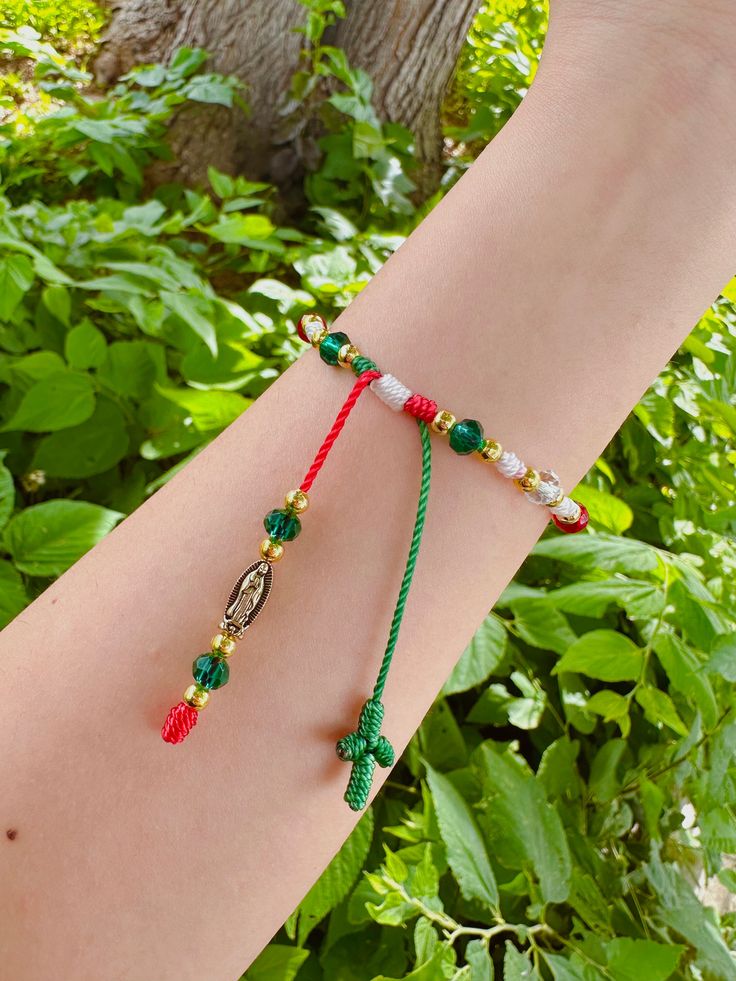 a woman's arm with two bracelets on it and a tree in the background