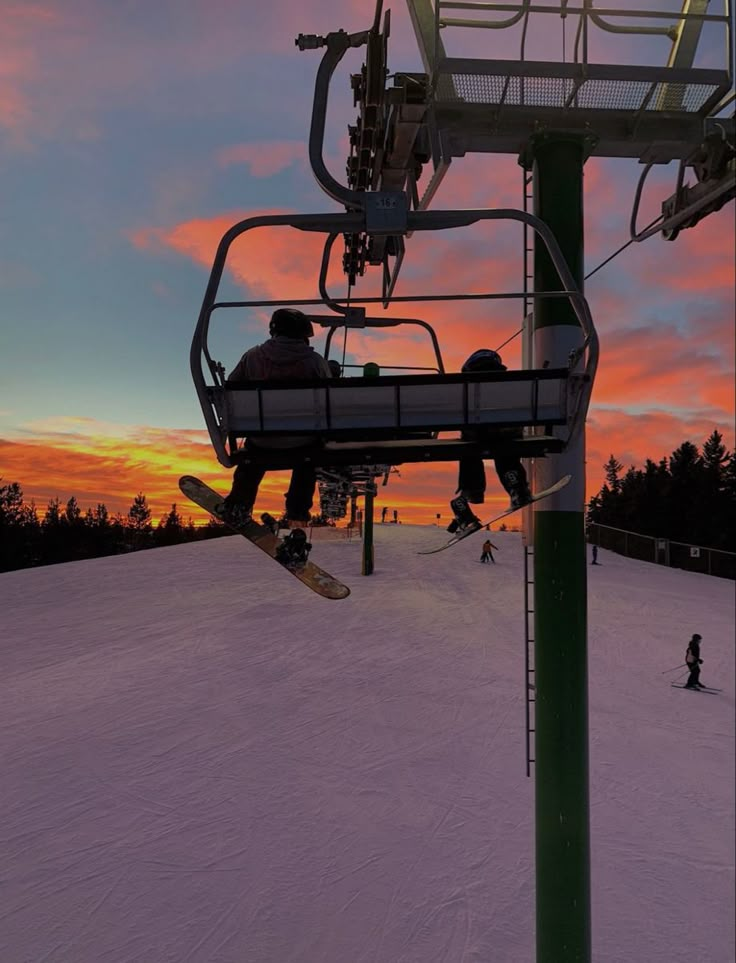 two people riding on a ski lift at sunset