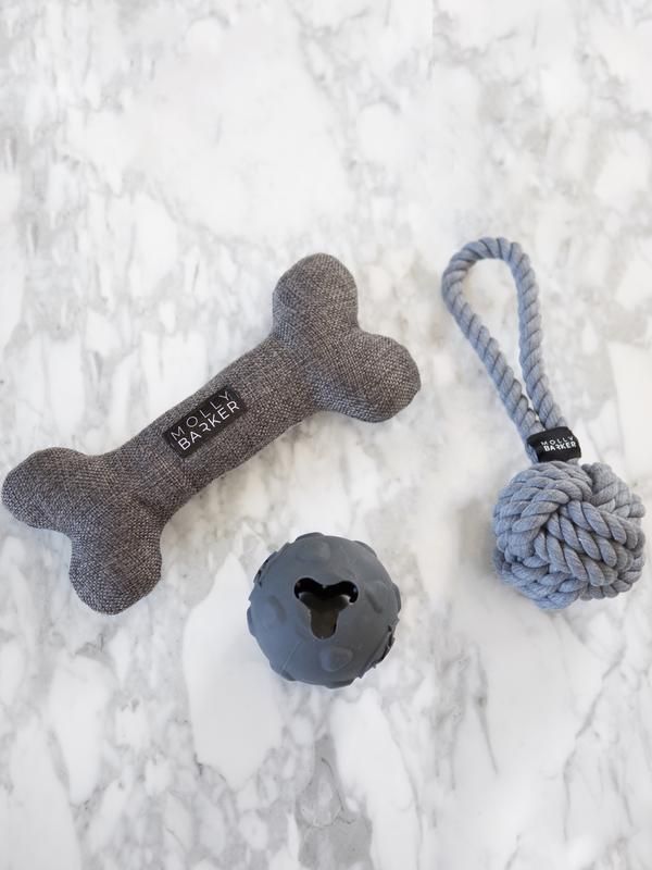 two dog toys are laying on a marble counter top, one has a bone and the other has a rope