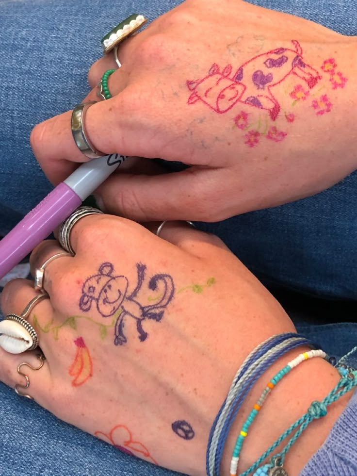 two people with tattoos on their hands and one has a purple pen in her hand