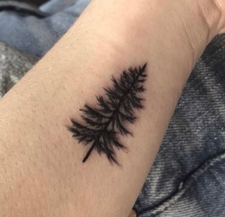 a small pine tree tattoo on the arm