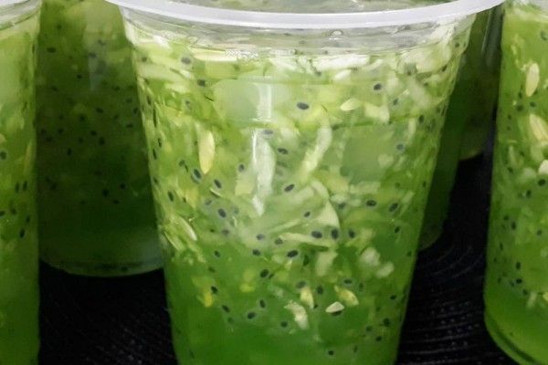 several cups filled with green liquid sitting on top of a black table next to each other