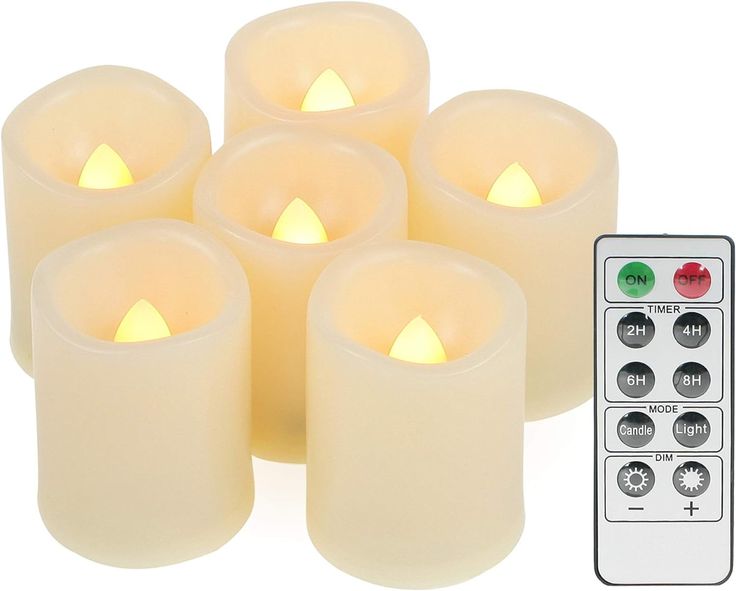 six lit candles with remote control on white background