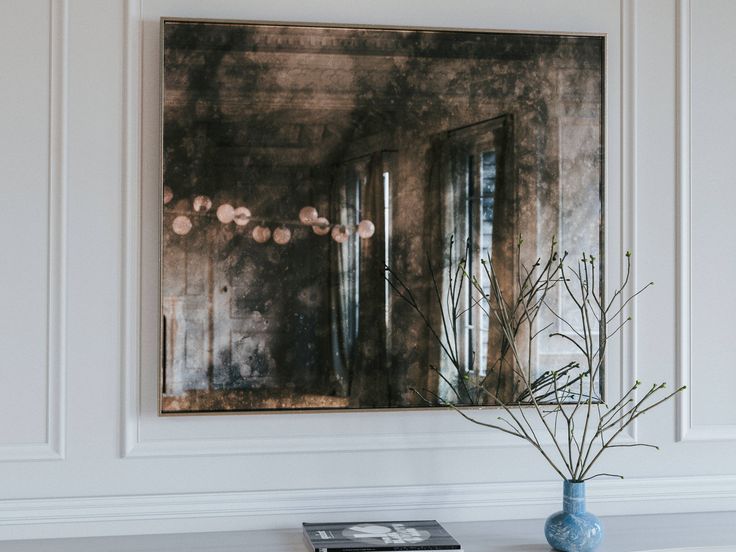 a blue vase sitting on top of a white table next to a mirror above it