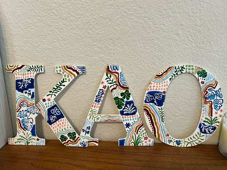 the letters are made out of wood and decorated with colorful flowers, leaves, and shapes