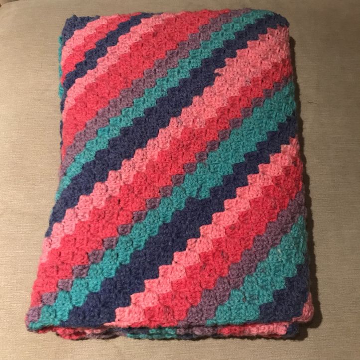 a crocheted blanket is laying on a couch