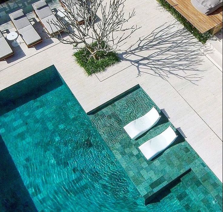 an aerial view of a swimming pool with lounge chairs