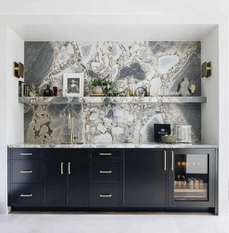 a kitchen with marble counter tops and gold accents on the wall, along with black cabinets