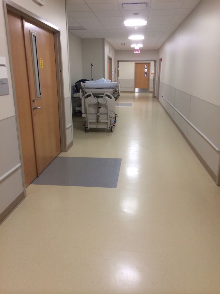 an empty hospital hallway with medical equipment on the floor and door to another room in the background