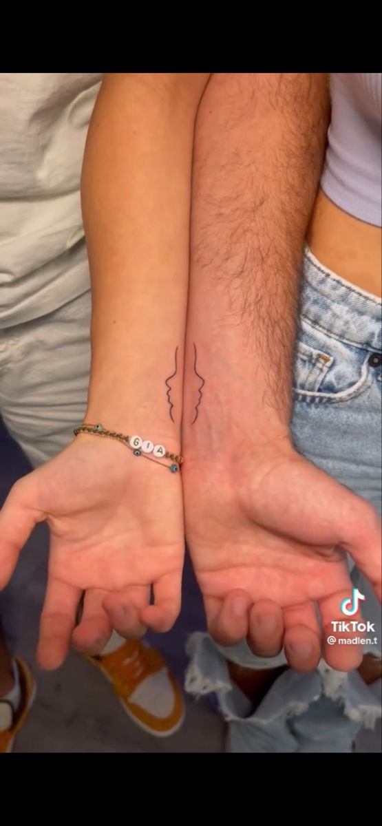 two people holding hands with tattoos on them