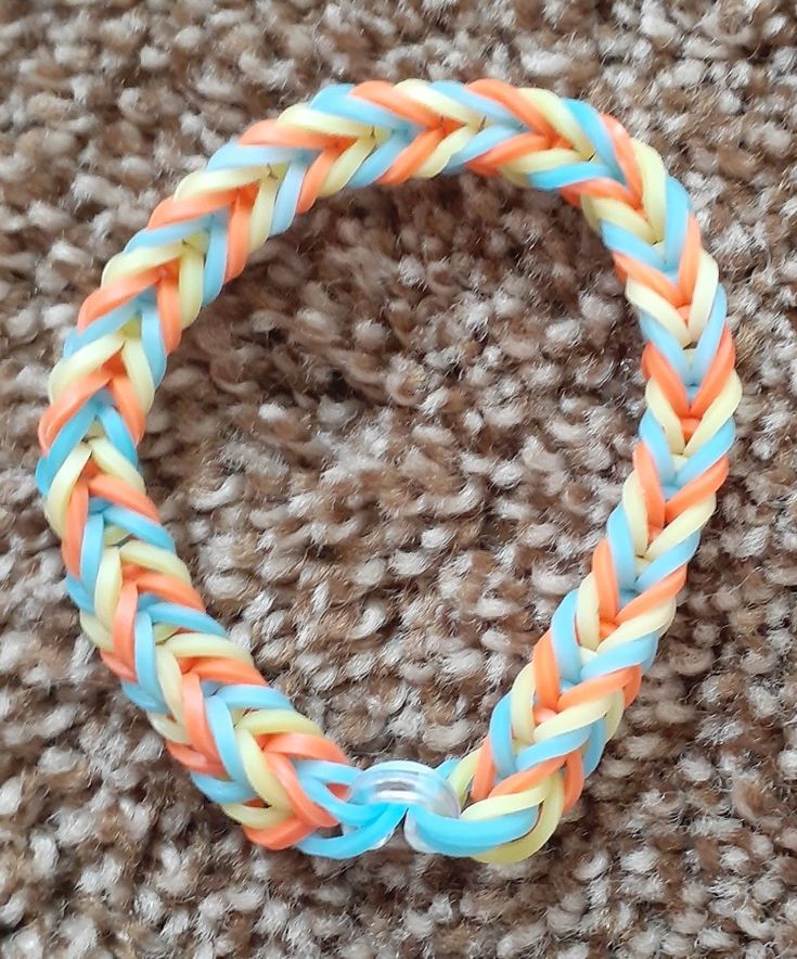 an orange, blue and yellow braided bracelet sitting on top of a brown carpet