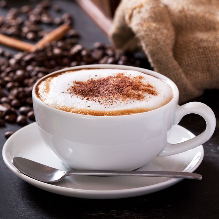 a cappuccino on a saucer next to coffee beans