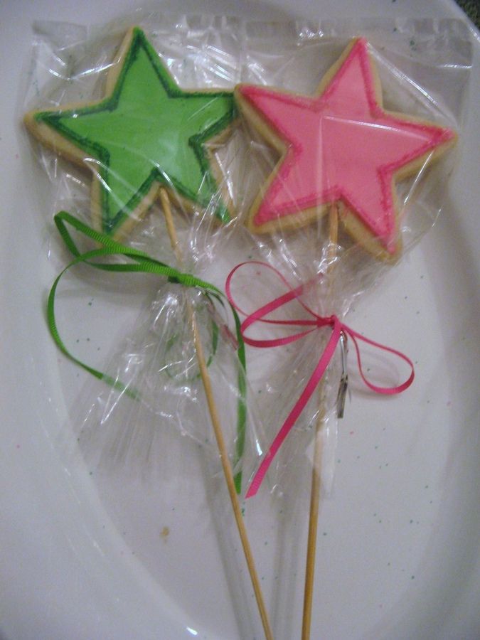 three decorated cookies on sticks in plastic wrappers