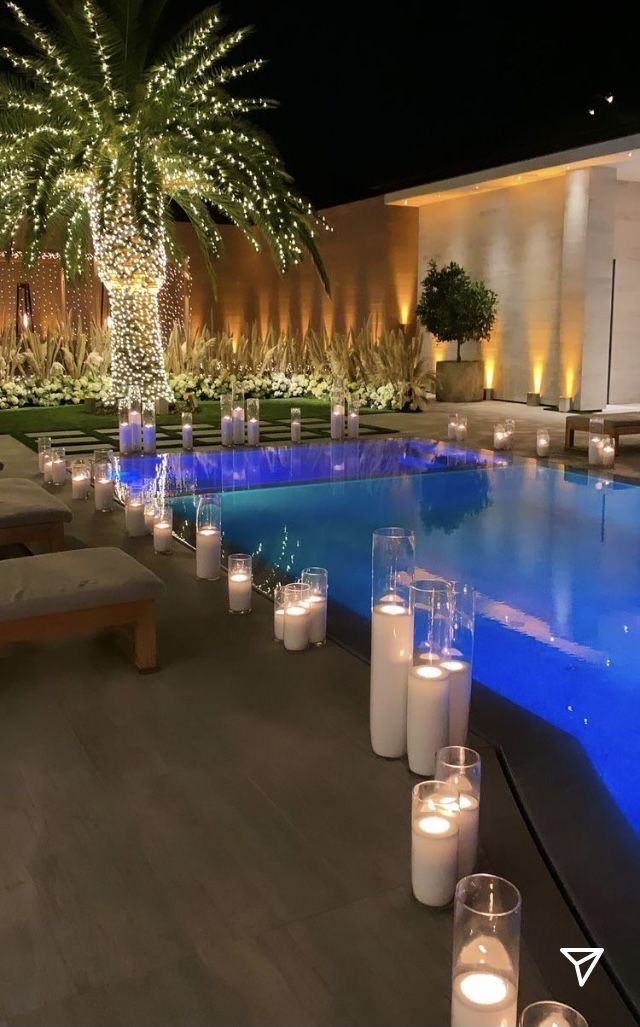 an outdoor pool with lit candles and palm trees