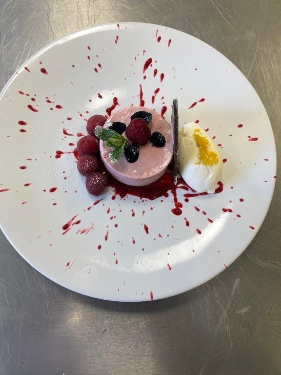 a white plate topped with fruit and whipped cream covered in red blood splatters