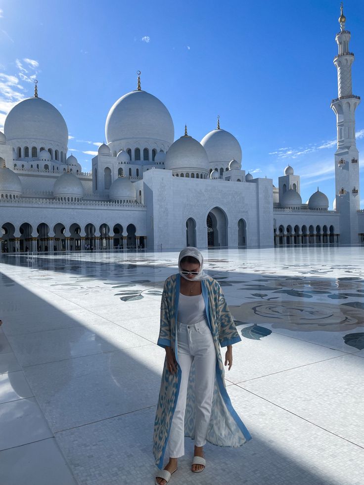 a woman standing in front of a white building with many arches and domes on it