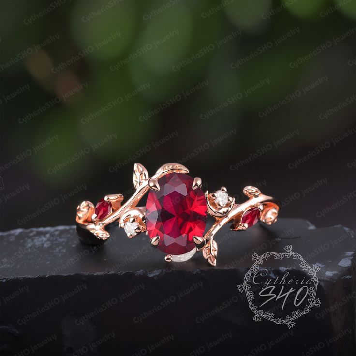 a red ring sitting on top of a black piece of wood with leaves around it