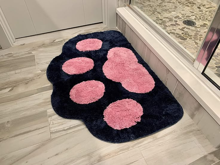 a blue rug with pink paw prints on the floor in front of a bathroom door