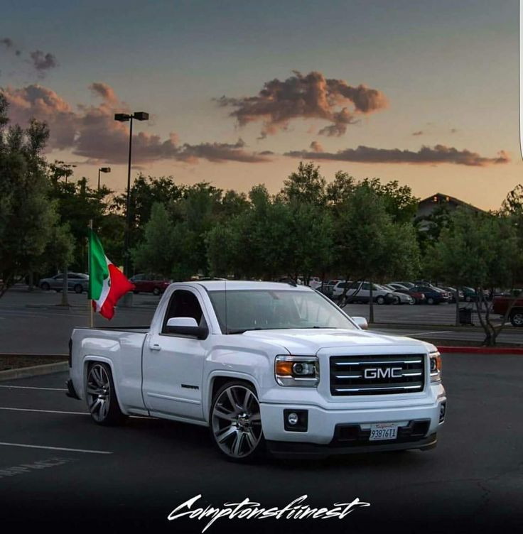 a white truck parked in a parking lot with a flag on it's side