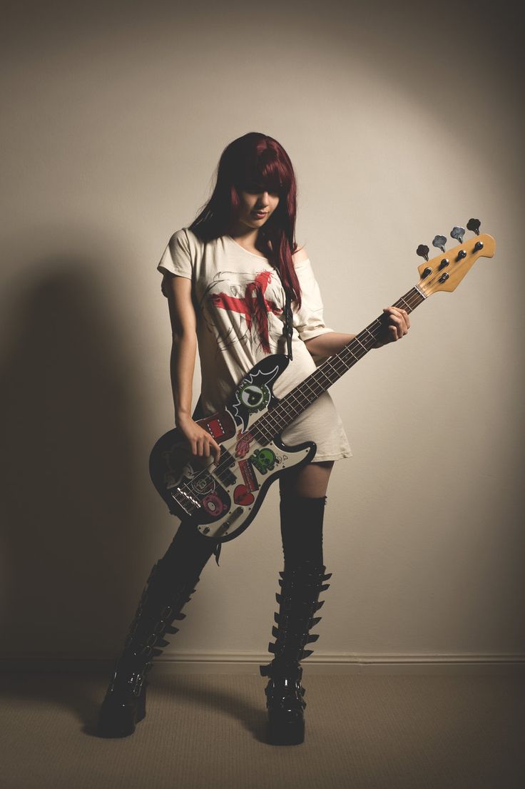 a woman with red hair and black boots is holding an electric guitar in her hands