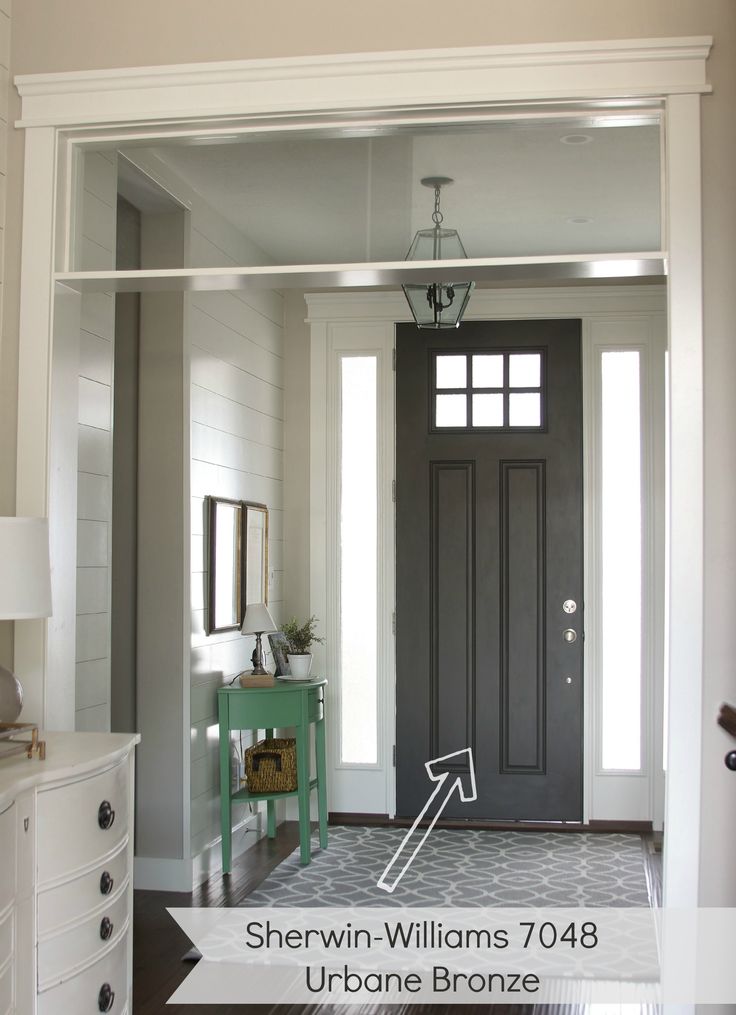 an entryway with a black door and white trim on the walls, along with a gray rug