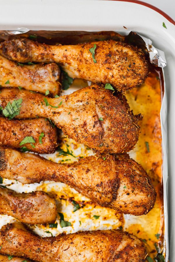 baked chicken legs in a casserole dish with cheese and parsley on top