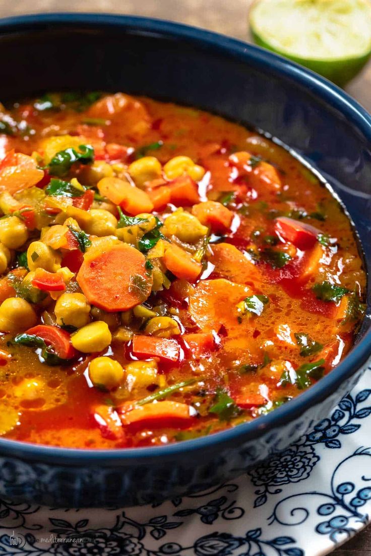 a blue bowl filled with vegetable soup on top of a plate