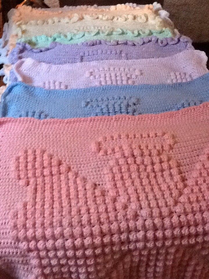 a group of knitted blankets sitting on top of a wooden table