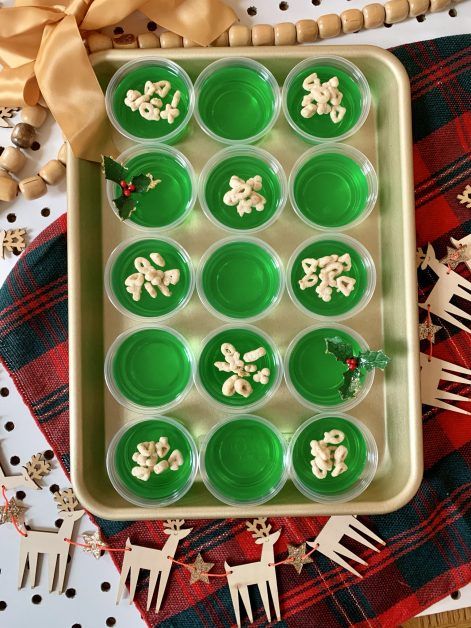 a tray filled with green cupcakes on top of a red and white table cloth