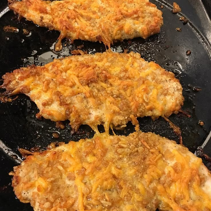 three pieces of chicken cooking in a frying pan