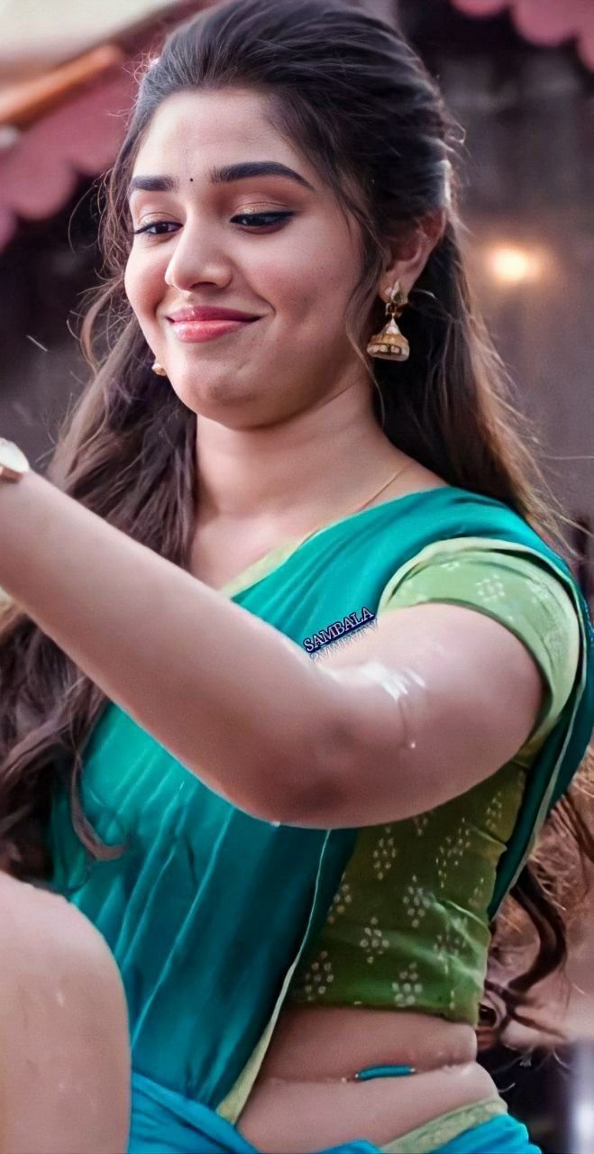 a woman in a green sari is brushing her hair and smiling at the camera