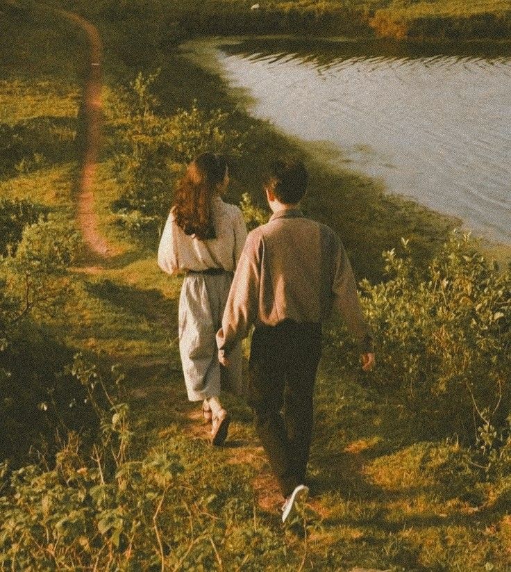 two people walking down a path near the water