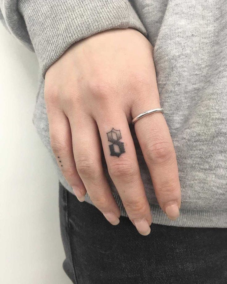 a woman's hand with a small black and white tattoo on her left ring