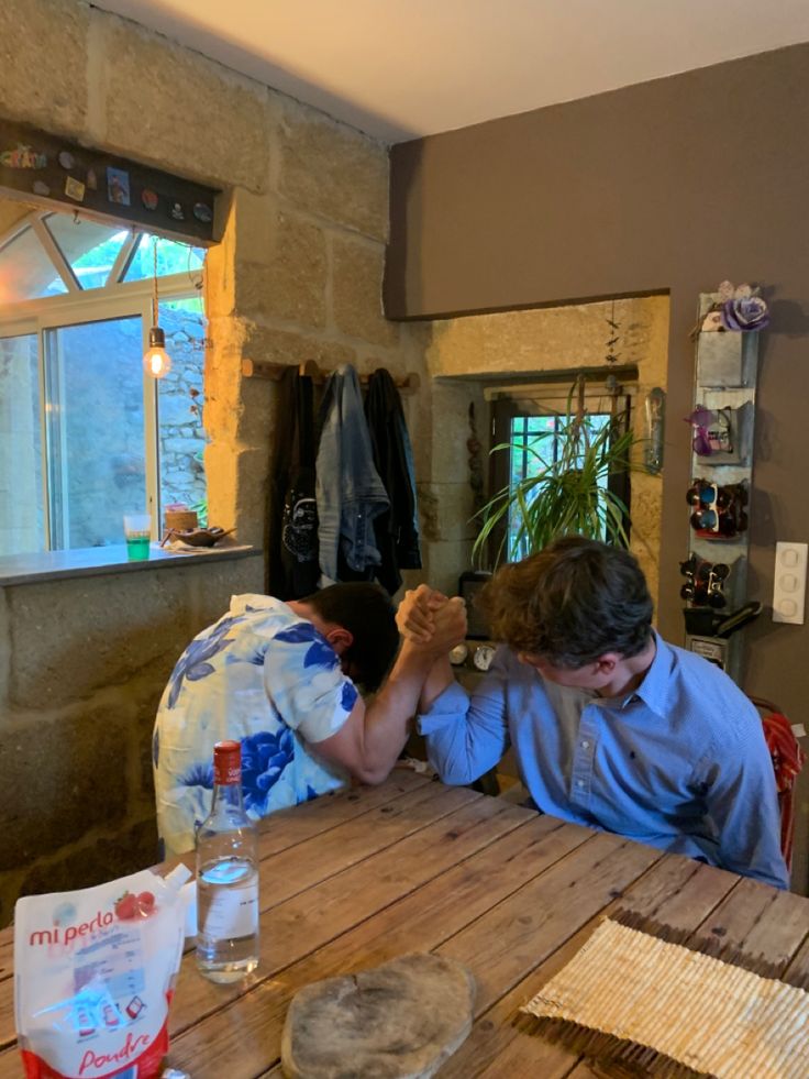 two people sitting at a wooden table in a room with stone walls and wood floors