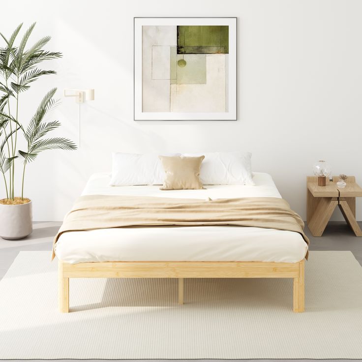 a bed sitting in a bedroom next to a table with a potted plant on it