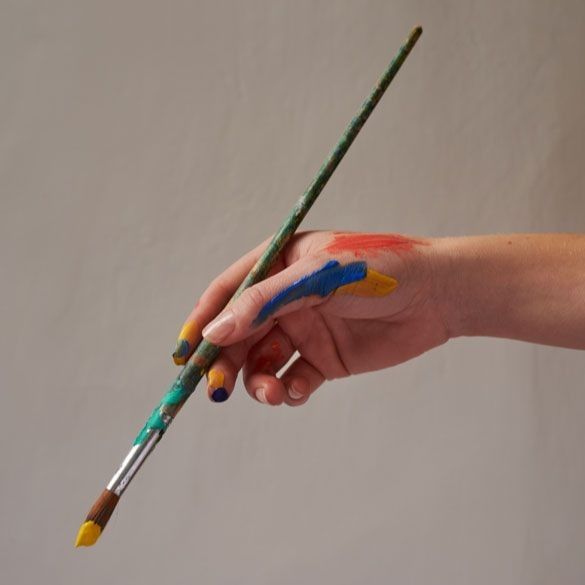 a person's hand holding two paintbrushes with different colors