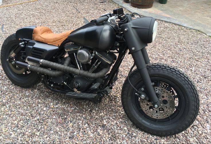 a black motorcycle parked on top of a gravel covered parking lot next to a building