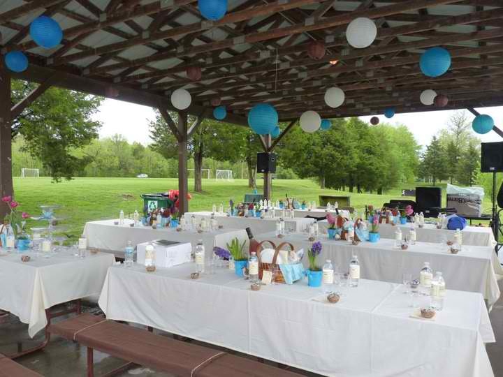 tables set up for an outdoor party under a pergolated area with blue and white decorations