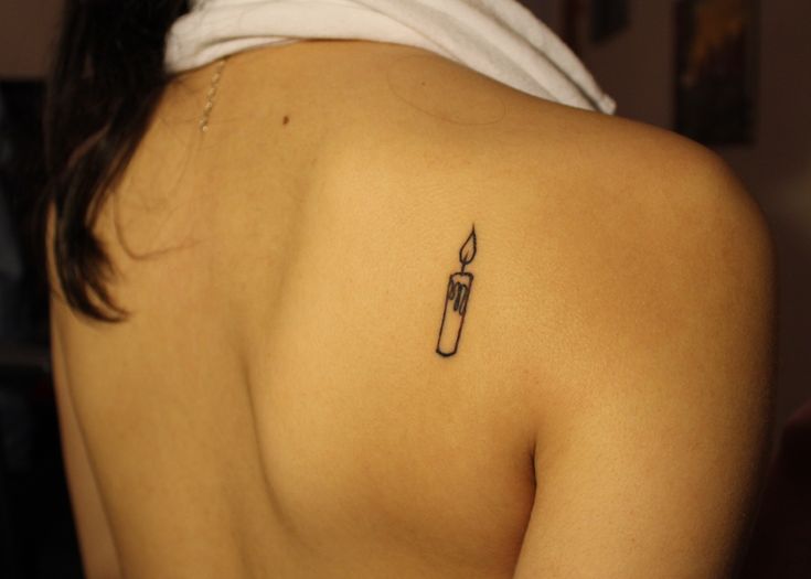 a woman with a small tattoo on her upper back shoulder and arm holding a lighter