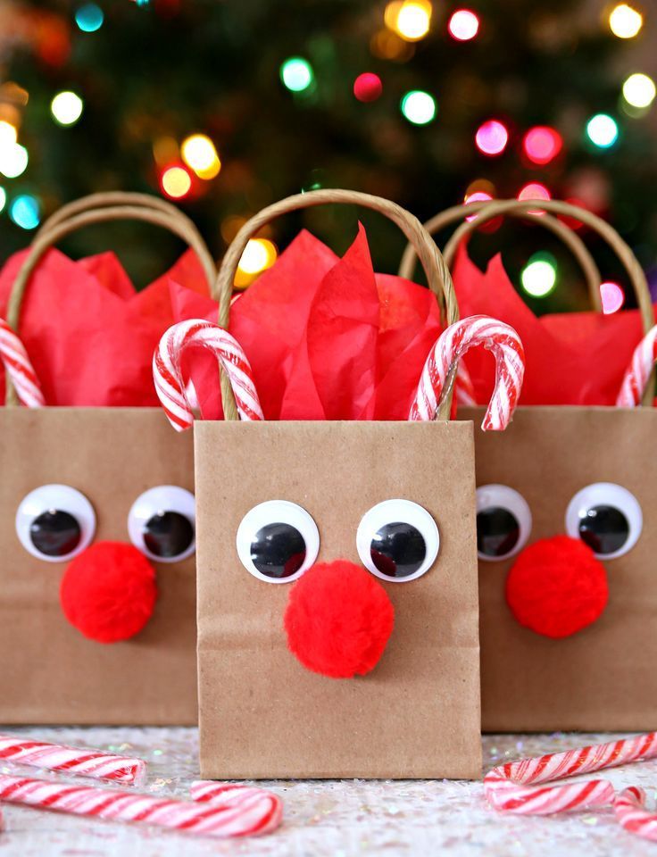 two paper bags with faces and candy canes in front of a christmas tree